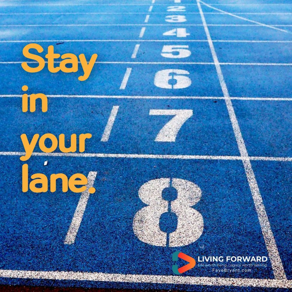 PIcture of a running track, having eight lanes, marked with white on a blue turf surface. The words "Stay in your lane" are superimposed on the photo.